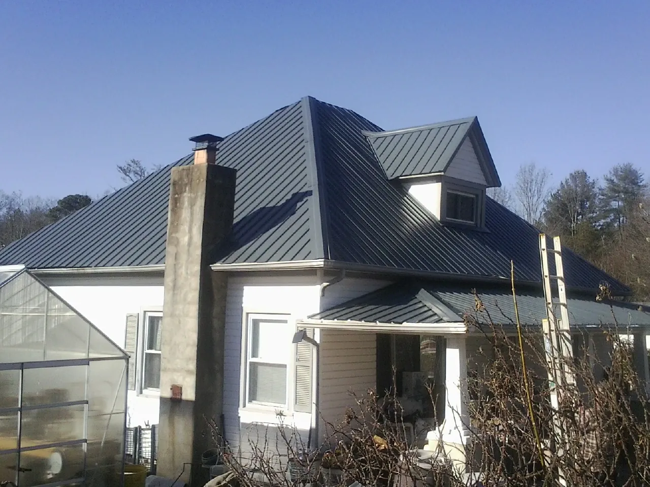 Dark blue standing seam metal roof on a white farmhouse with dormer — Slate & Tile Roof Repair by Roofing Brothers in Hanoverton