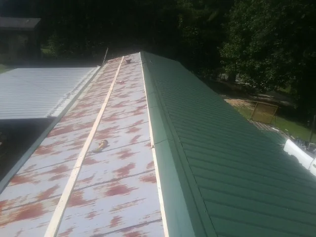 Old rusted panels beside newly installed green metal roofing — Wind Damage Roof Repair by Roofing Brothers in Hanoverton