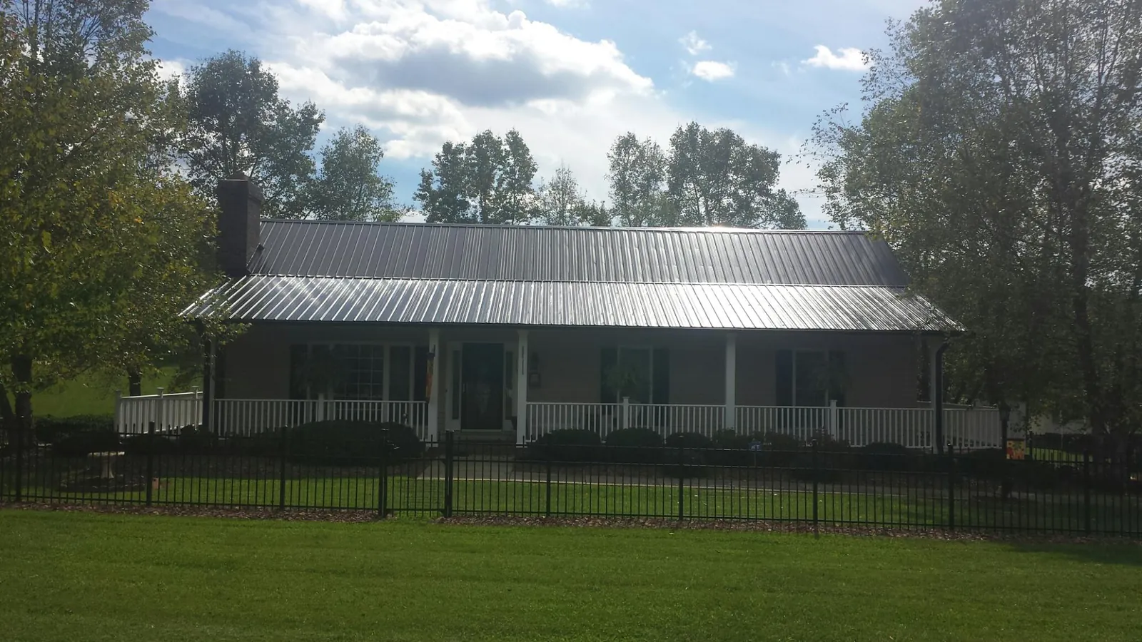 Gray metal roof on a brick ranch with a full width front porch — Gutter Guard Installation work by our crew in Hanoverton