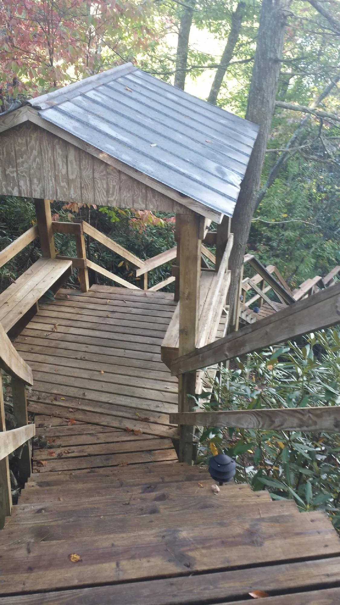 Metal roofed shelter over wooden steps on a wooded walkway — Skylight Repair & Installation work by our crew in Hanoverton